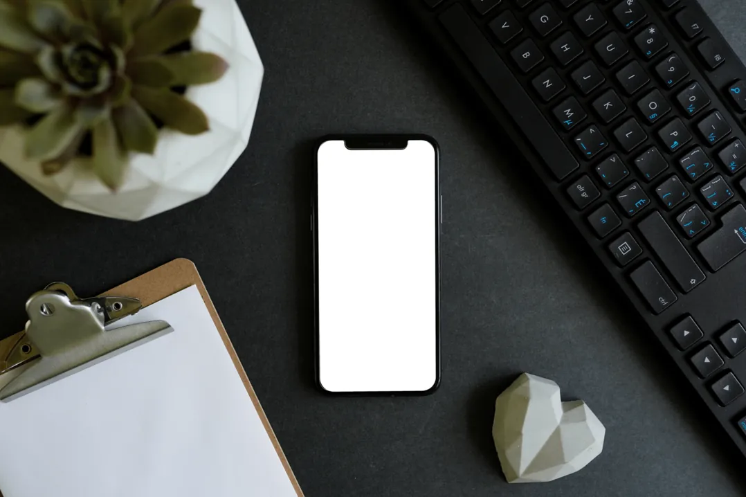 Smartphone und Tastatur auf einem dunklen Schreibtisch