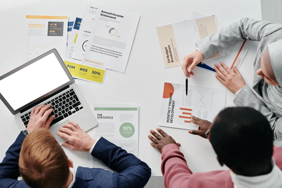 Vier Personen besprechen Auswertungen und Diagramme an einem Tisch
