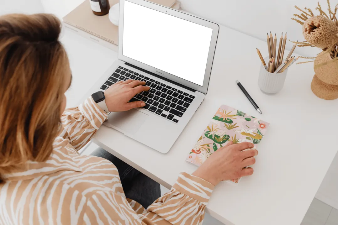 Blick über die Schulter auf einen Laptop am hellen Arbeitsplatz